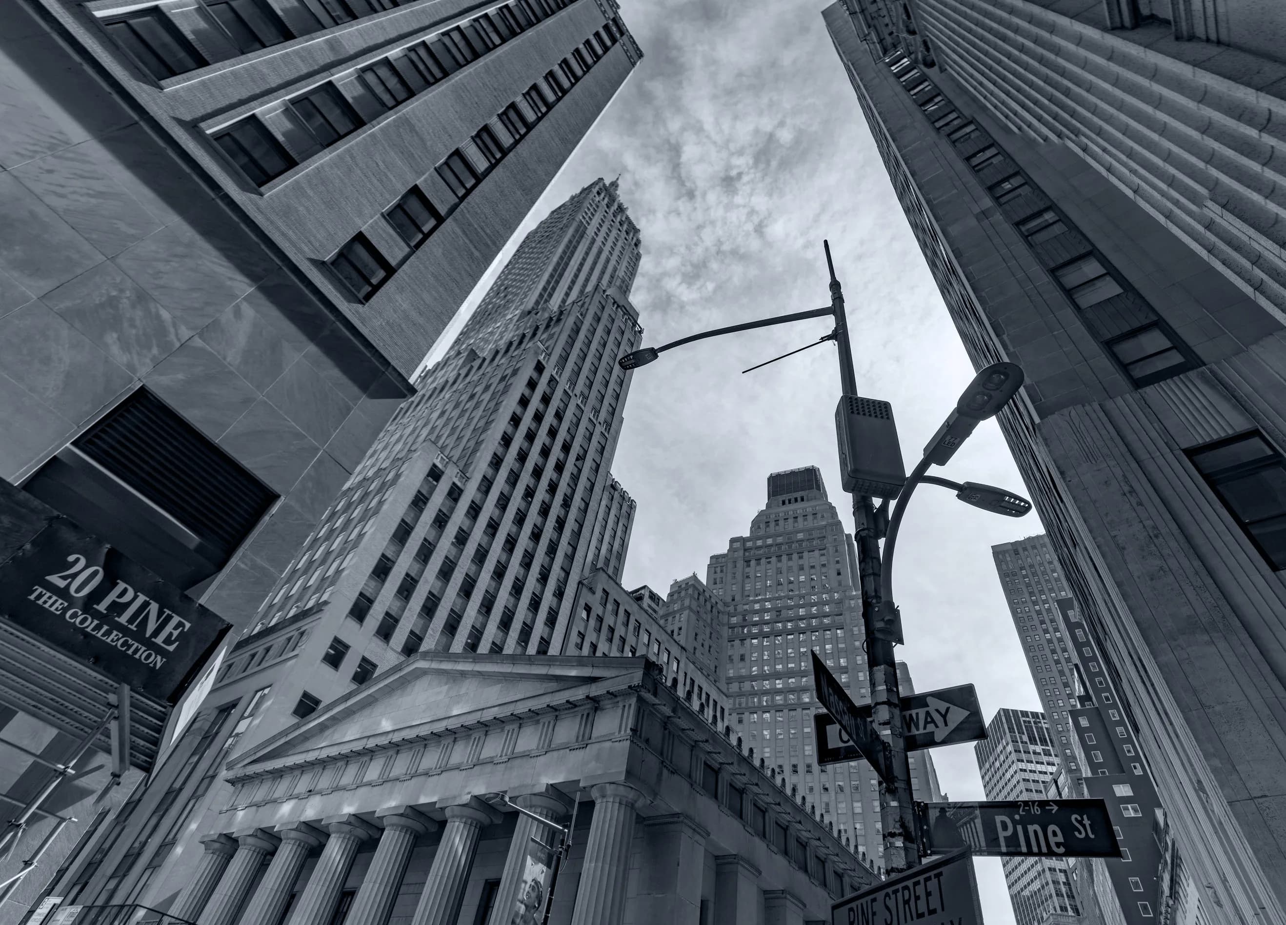 Black-and-white upward view of Wall Street towers around Pine Street in Lower Manhattan.