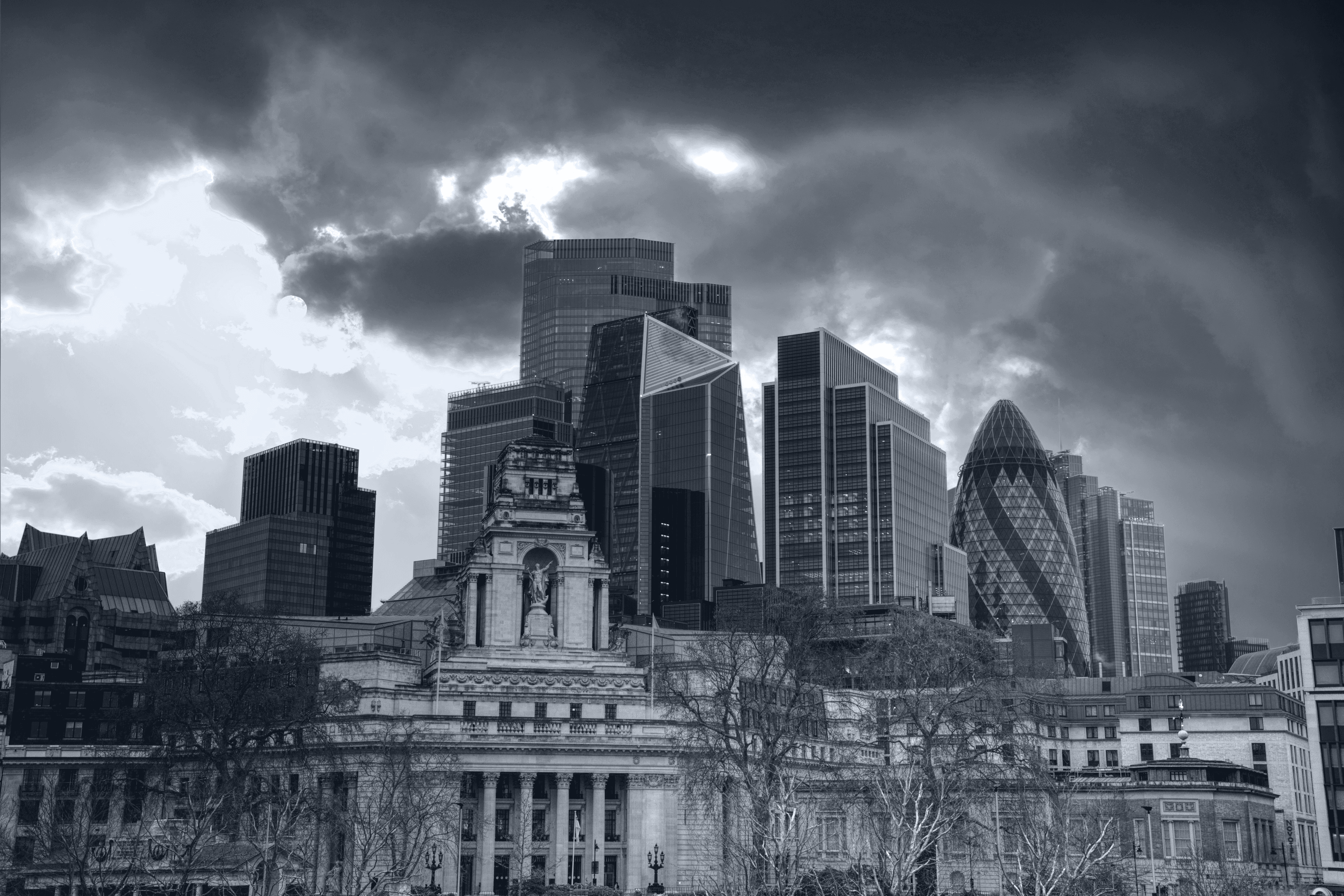 City of London towers above historic buildings beneath a dramatic clouded sky