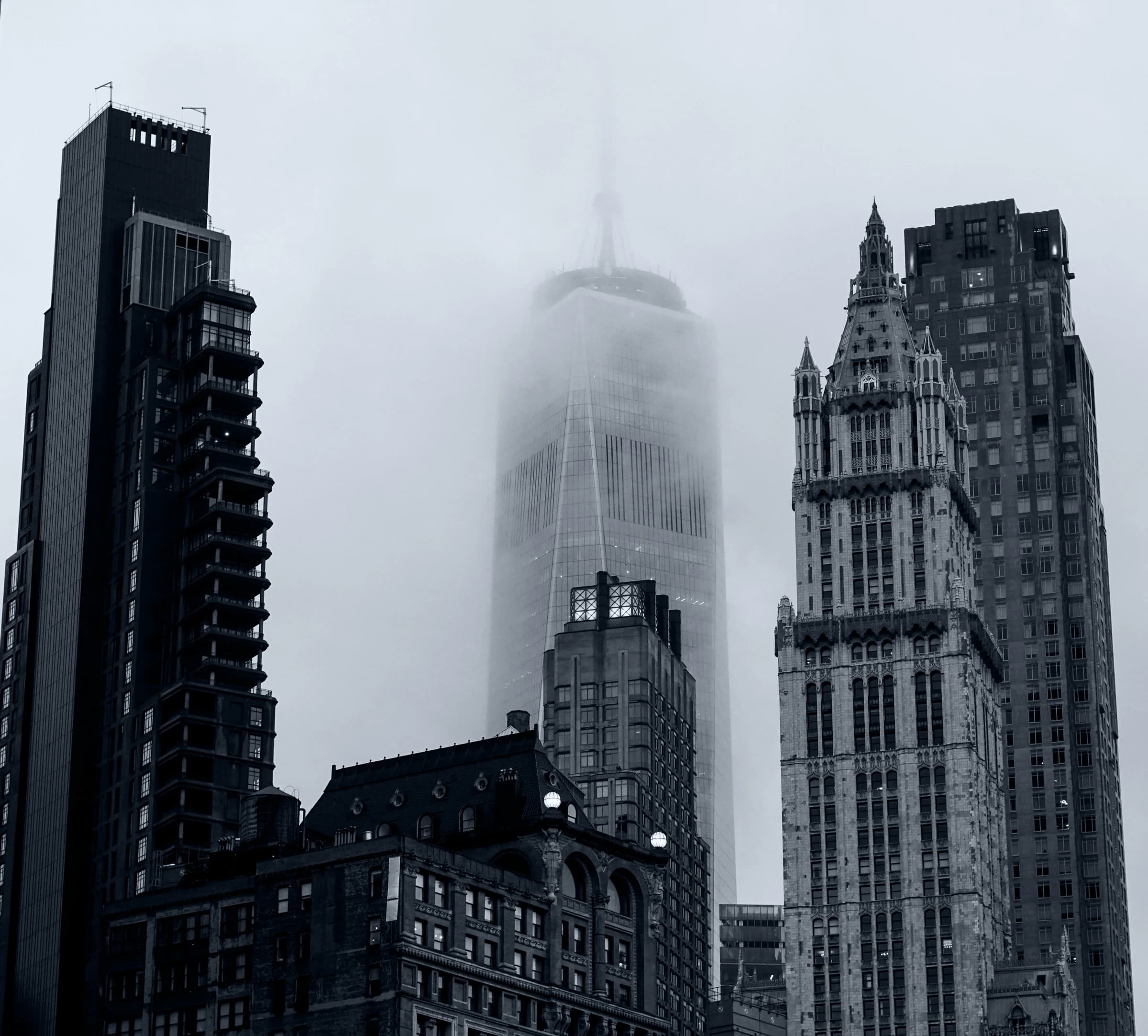 Black-and-white view of New York skyscrapers rising into low cloud.